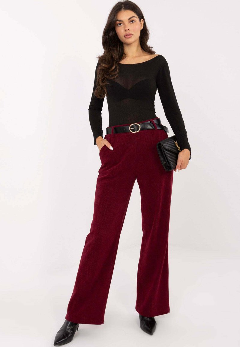 Czarna bluzka z długim rękawem, przezroczysta faktura. Bordowe spodnie o szerokich nogawkach z kieszeniami, prążkowany materiał. Czarny pasek z okrągłą sprzączką. Czarna torebka i czółenka na szpic.