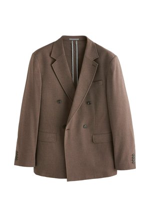 Man in brown double-breasted blazer adjusting cuff, showing dark buttons and textured fabric on neutral background.