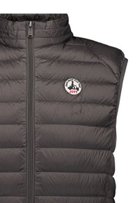 Gilet nero trapuntato senza maniche con cerniera frontale e toppa rotonda con logo che mostra uno scooter e il testo "Just Over The Top JOTT" sul petto.