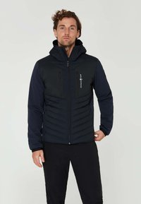 Marinblå pufferjacka med huva, med dragkedja fram, två bröstfickor och en design med texturerade paneler. Slät tyg och en strömlinjeformad passform.