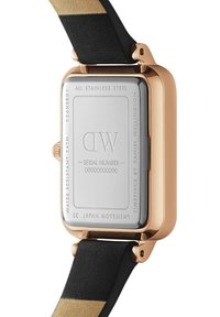 Gold-toned stainless steel watch case with a rectangular shape, black and gold strap, and a smooth metallic back featuring engraved details.