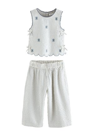 Mouwloze witte top met blauwe verticale strepen, bloemrijke borduurwerk, zijstrikjes en bijpassende witte gestreepte losse broek met elastische taille.
