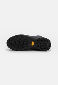 Czarna gumowa podeszwa z głębokim bieżnikiem dla lepszej przyczepności, z żółtym logo Vibram. Solidny i teksturowany design zapewniający trwałość.