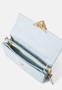 Portafoglio in pelle blu chiaro con hardware dorato. Presenta un compartimento con zip e più slot per carte all'interno. Tessuto liscio, dettaglio a chiusura triangolare.