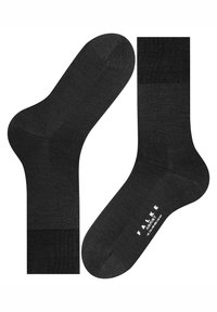 Svarta bomullssockor med ribbad mudd, slät textur och förstärkt häl och tå. Har logotypen "FALKE AIRPORT" på sulan.