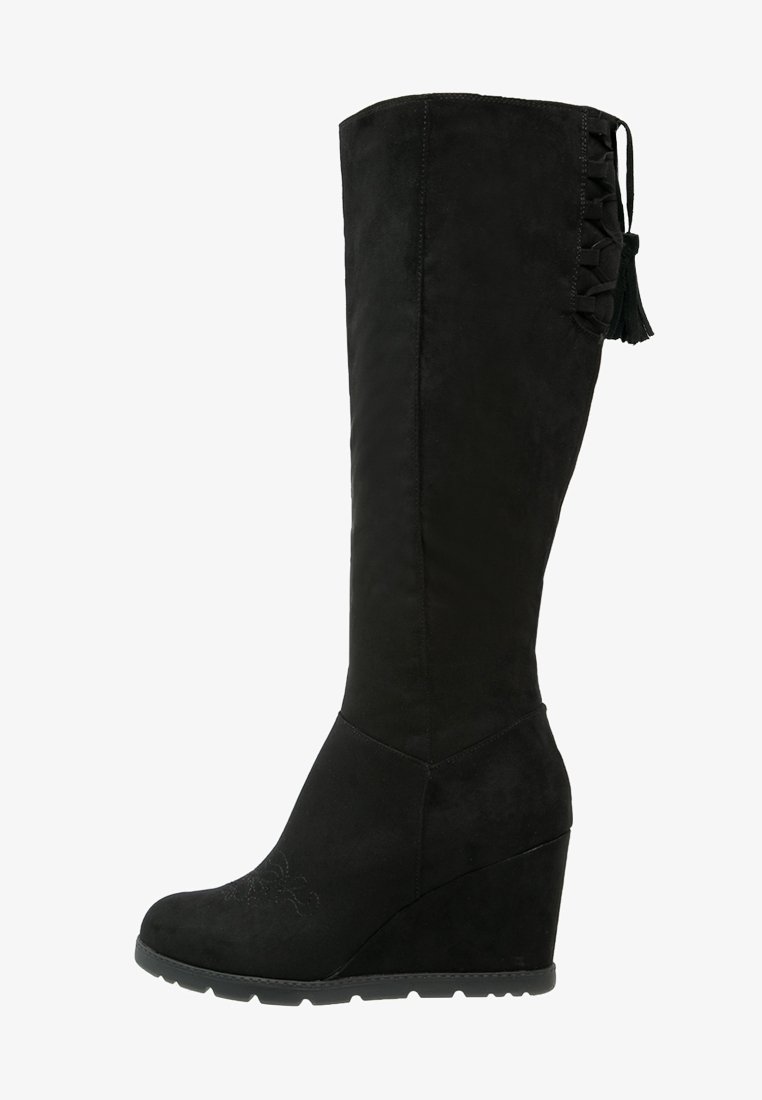 Botas de cuña altas hasta la rodilla, de ante negro con un acabado texturizado, que presentan un detalle de cordones y un adorno de borlas en el costado.