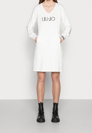 Hvid sweatshirt-kjole med lange ærmer, V-hals med "LIUJO" i sorte rhinsten og sidelommer. Bæres med sorte ankelstøvler.