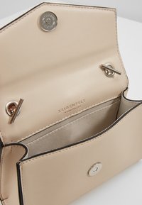 Borsa a mano in pelle color beige con una texture liscia, ferrature argentate e una chiusura centrale. L'interno presenta una fodera morbida e scomparti.