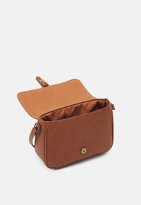Brun syntetisk crossbody taske med magnetlukning, blød indvendig foering og justerbar rem, der har en simpel rektangulær form.