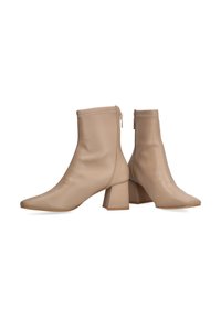 Botas de tobillo de imitación de cuero en color beige, con punta afilada, forma estructurada y tacón cuadrado. Cuentan con un cierre lateral y una textura suave.