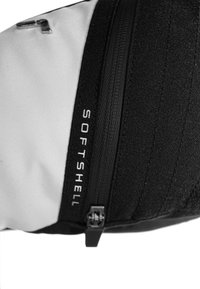 Black and white softshell bag with a textured surface, featuring a curved shape, metal zipper, and the word "SOFTSHELL" printed vertically.