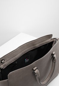 Šedá kožená kabelka se zipovým vrchem, černým interiérem a dvojitými uchy. Obsahuje štítek s logem uvnitř a hladkou texturu.