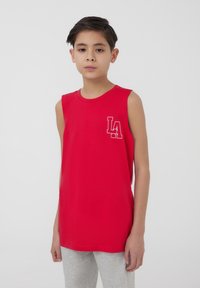 Maglietta rossa senza maniche in cotone con scollatura rotonda e logo "LA" bianco stampato sul petto. Abbinata a pantaloni della tuta grigi.