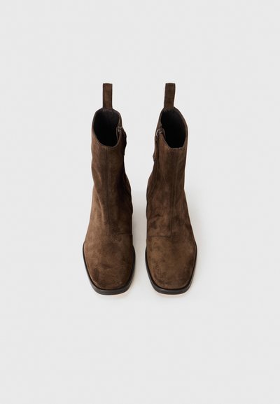 Bruna mocka anklar med en slät textur, formade med en fyrkantig tå, med en sidodragkedja och en dragflik på hälen.