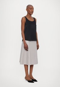 Black sleeveless top, gray knee-length skirt, black pointed shoes. Smooth fabric, simple design, and fitted silhouette.