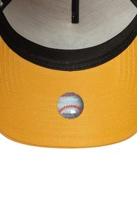 Casquette de baseball jaune avec une doublure noire, arborant une étiquette ronde représentant un baseball sur le dessous de la visière.