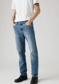 Jeans de mezclilla azul claro con un diseño clásico de pierna recta. Cuenta con cuatro bolsillos, una cinturilla con pasadores para cinturón y una textura desvaída.