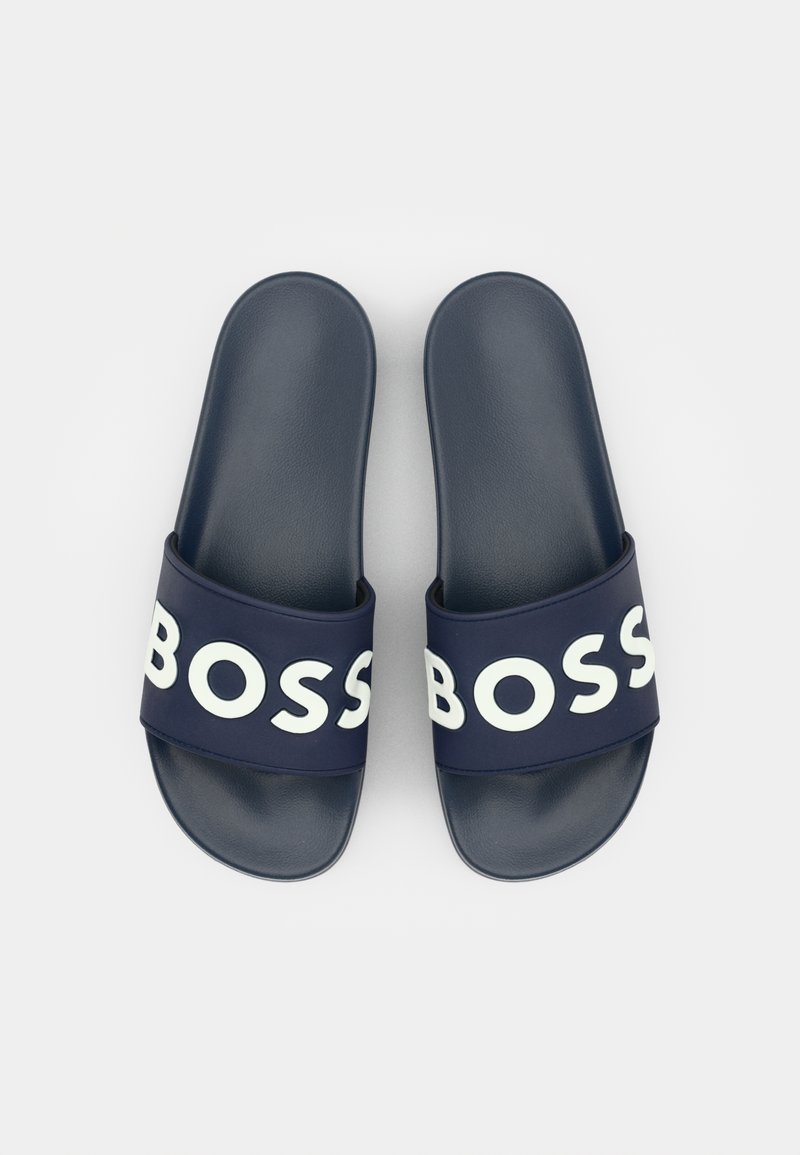 Sandales à glissière bleu marine avec une large bande présentant le grand lettrage blanc "BOSS". Matériau synthétique lisse, forme élégante et design ouvert à l'avant.