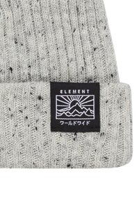 Berretto grigio lavorato a maglia con una texture a coste, dotato di un'etichetta nera con un graphic di montagna e testo giapponese. Design semplice con filato spruzzato.