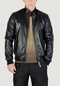 Černá kožená bomber bunda se zipem vpředu, klopou na knoflíky, bočními kapsami, žebrovanými manžetami a švy na ramenou. Hladká textura s přiléhavým střihem.
