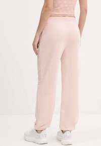 Lichtroze sweatpants met een ontspannen pasvorm, taps toelopende boorden en een elastische tailleband. Gemaakt van zachte stof met een gladde textuur.