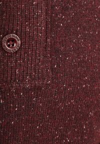 Bordeauxrode gebreide stof met een geribd patroon en lichte kleurvlekken; omvat een ronde, wijnrode knoop met het label "STATE OF ART."