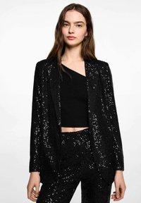 Svart paljettblazer med en slät yta, med en klassisk kragsdesign och strukturerad passform, som kombineras med en svart ribbad crop top.