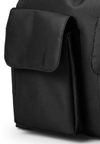 Svart nylontygs väska med texturerad yta, som har en stor klaffficka och sidoficka, förstärkt sömnad och släta kanter.