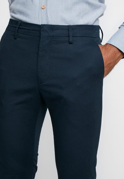 Chinos azul-marinho feitos de um tecido suave, com frente lisa, passantes para cinto e bolsos laterais, com um design de corte slim e um fecho de correr oculto.