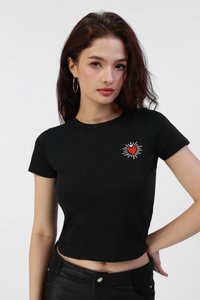Black cropped t-shirt in ribbed fabric, featuring a red heart graphic with radiating lines. Short sleeves and a round neckline.