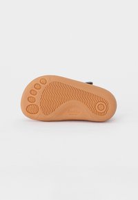 Braune flexible Gummisohle mit strukturiertem Griffmuster und kreisförmigen Akzenten. Bietet ein leichtes Design, das für barfußähnliches Schuhwerk geeignet ist.