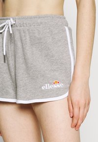 Pantaloni corti di cotone grigi con una coulisse bianca, bordo laterale bianco a contrasto e un logo colorato ricamato sulla parte bassa della gamba sinistra.