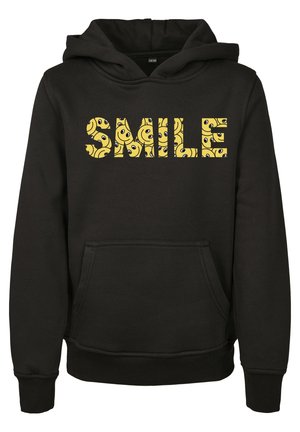 Sort hættetrøje med forlommer og ordet "SMILE" i gule bogstaver fyldt med mønstre af smilende ansigter.