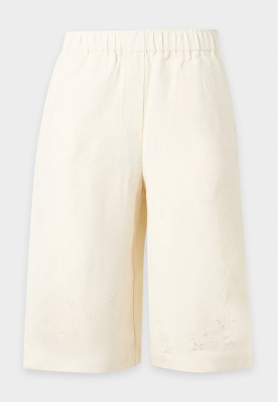 Shorts couleur crème longueur genoux avec ceinture élastique et broderie florale subtile près de l'ourlet sur fond uni.