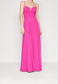 Robe longue ajustée de couleur rose avec un décolleté en cœur, des fines bretelles et des détails froncés au niveau du bustier, s'évasant en une jupe ample.