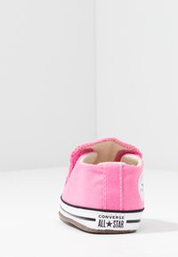 Rožinės kanvasinės sportbačiai su balta guma, juodomis juostelėmis ir "Converse All Star" ženklu ant kulno. Šiek tiek tekstūruotas audinio paviršius.