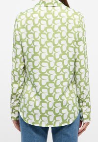 Camicia a maniche lunghe verde e bianca con un motivo astratto di ovali sovrapposti, realizzata in tessuto morbido e con un orlo curvo.