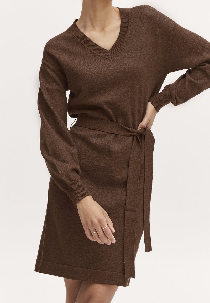 Vestito marrone lavorato a maglia con scollo a V, maniche lunghe e cintura in vita annodata. Presenta polsini a coste e orlo dritto.