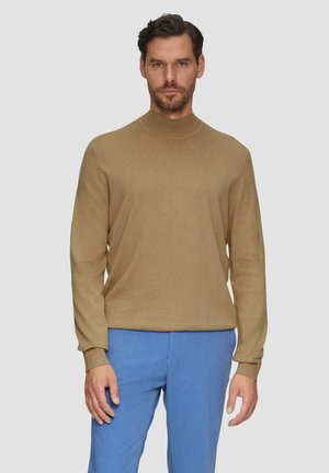 Pull à col roulé léger marron avec un col côtelé, des manches ajustées et une texture lisse, associé à un pantalon bleu clair.