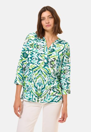 Blusa colorida con un vibrante patrón verde y azul, fabricada en tejido ligero, con mangas tres cuartos y un escote abotonado.