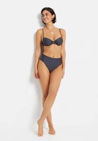 Tamsiai pilkas bikini rinkinys, turintis struktūrizuotą, su lankeliais viršutinę dalį su plonomis petnešėlėmis ir aukštu liemeniu kelnes, pagamintas iš lygaus, tamprios medžiagos.