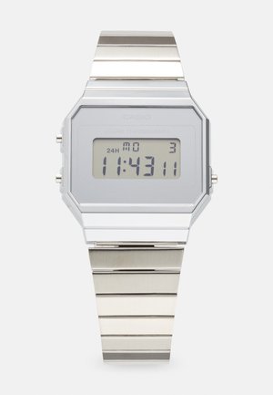 Silver Casio digital watch with an octagonal case, a gray LCD display, and a metal link bracelet. Features include an alarm and chronograph functions.