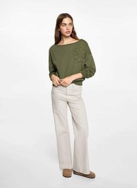 Olijfgroen sweatshirt met oversized halslijn, geborduurd bloemdetail, gecombineerd met lichtbeige flared jeans en bruine enkellaarsjes.