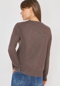 Brązowy sweter dziany z długimi rękawami i okrągłym dekoltem. Tekstura jest gładka, z lekko luźnym krojem i ribbowanym wykończeniem.
