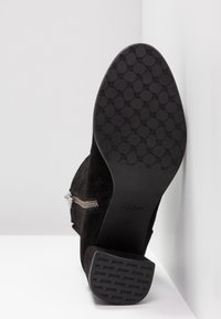 Botte en daim noir avec une fermeture éclair latérale, montrant la semelle à motif et le talon bloc embossé avec "JOOP!" et la taille 37.