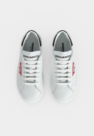 Paire de baskets en cuir blanc avec lacets blancs, détail talon noir, logo latéral rouge et texte "DSQUARED2" sur la languette.
