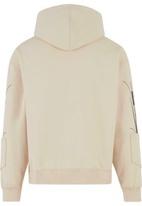 Hettegenser i lys beige stoff med en glatt tekstur, med svarte linjedetaljer på ermene og en lappelomme på siden.