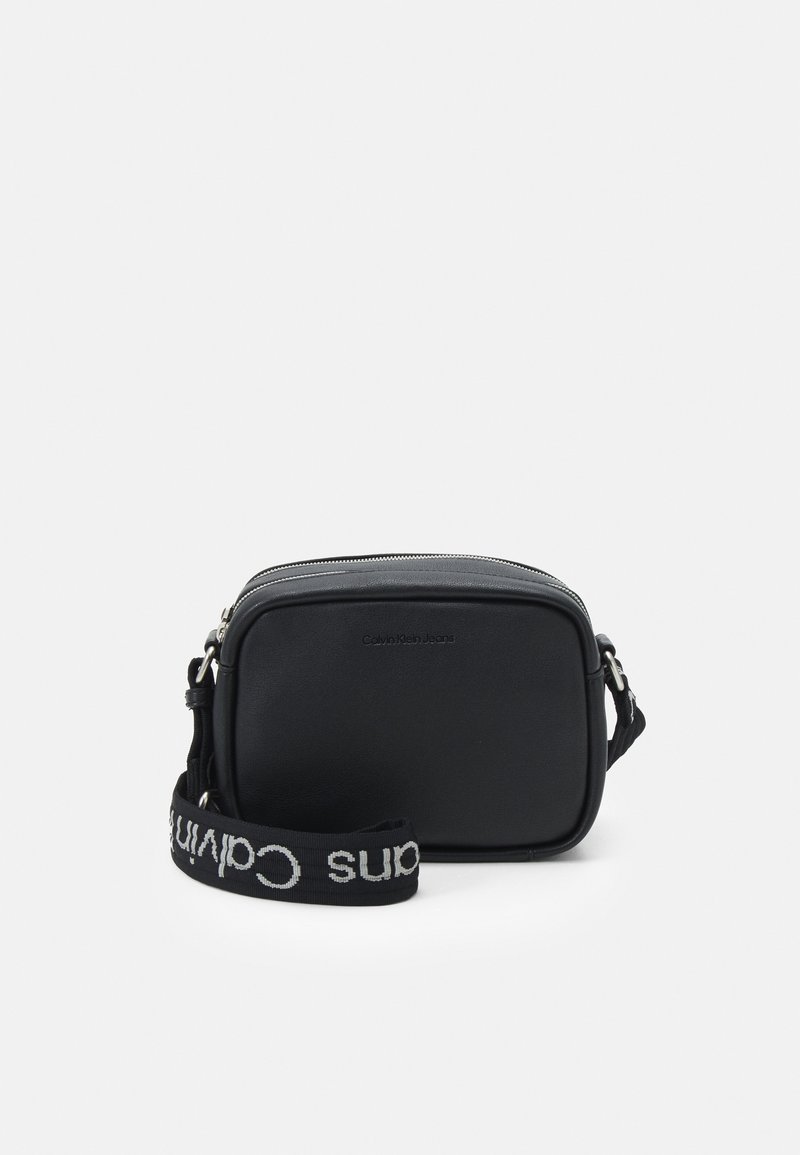 Borsa a tracolla nera con una texture sintetica liscia, forma rettangolare, chiusura con zip e una tracolla intrecciata con il logo "Calvin Klein".