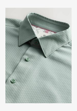 Hellgrünes Hemd mit Knöpfen und strukturiertem Muster, ausgestattet mit einem Umlegekragen und grünen Knöpfen. Innenmuster ist am Kragen sichtbar.