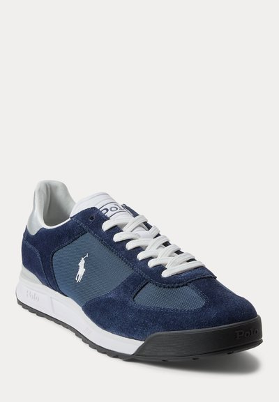 Navyblauwe en witte Polo sneaker met suède en mesh panelen, witte veters en het Polo-logo op de zijkant en tong, schuine aanzicht.